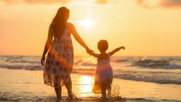 En mor som er enslig forsørger og dattera koser seg på stranda
